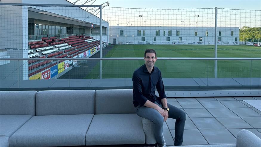 Alexander Gruber an seinem Arbeitsplatz in Wien Aspern. Im Hintergrund ist das Hauptfeld des ÖFB Campus zu sehen. 