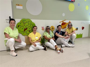 Angstfrei und vertrauensvoll. Primar Ernst Prethaler und sein Team in der neuen bunten Arbeitskleidung, unkonventionell sitzend auf Augenhöhe mit den Kindern.