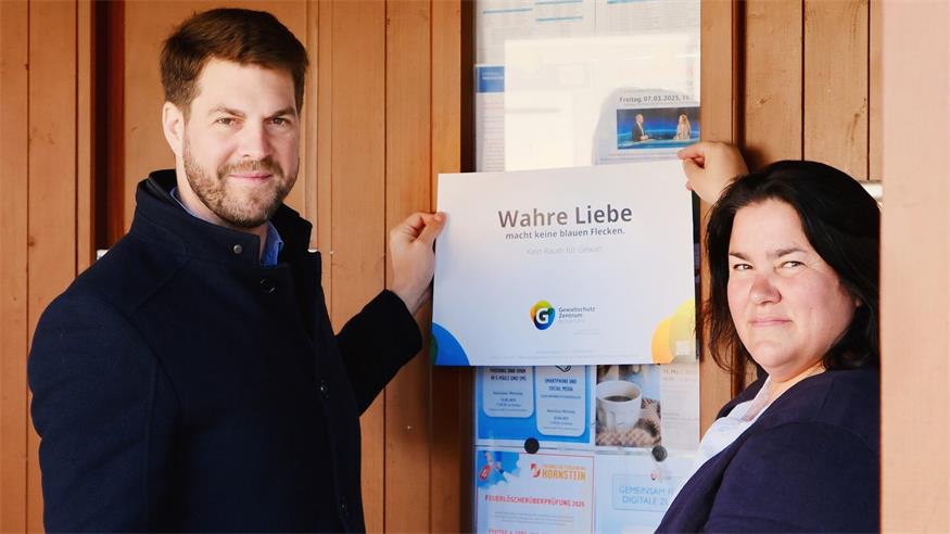 Bürgermeister Christoph Wolf und Gewaltschutzbeauftragte Elisabeth Szorger mit Plakaten zur Aktion "Wahre Liebe macht keine blauen Flecken".