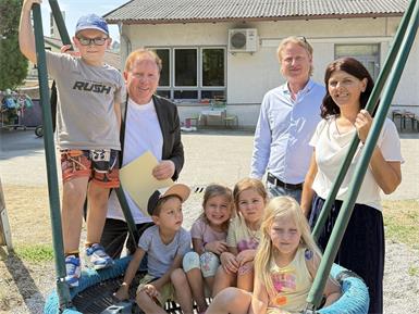 Bürgermeister Matthias Weghofer, Amtsleiter Christoph Kroyer und Kindergartenleiterin Belinda Grill freuen sich mit den Kindern über mehr Platz im Außenbereich des Kindergartens. 
