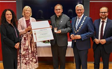 Bürgermeister Thomas Steiner überreichte im Beisein von Vizebürgermeister Istvan Deli, Vizebürgermeisterin Charlotte Toth-Kanyak sowie Magistratsdirektorin Gerda Török Urkunde und Ehrenring an Pater Achim Bayer