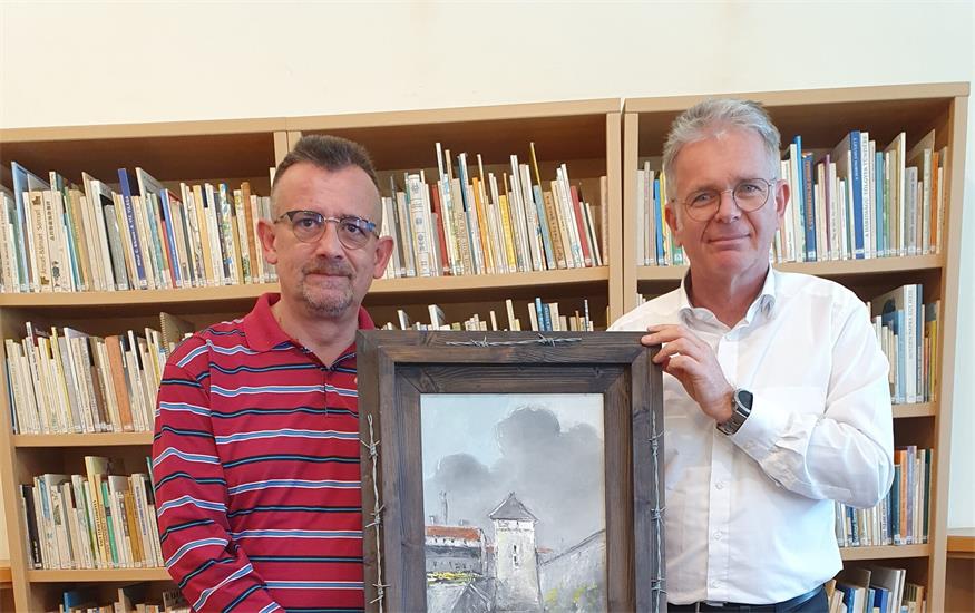 Der Verein „Lila Winkel“ vertreten durch Bernd Gsell übergab das Bild als Leihgabe an das UMIZ. Institutsleiter Ladislaus Kelemen nahm das Bild mit Freude entgegen. Es soll im UMIZ einen Ehrenplatz bekommen und fortan der Öffentlichkeit zugänglich sein.