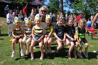 Die Kinder wie Marie, Luisa, Lena, Mia-Lina, Emilia, Emma und Sarah -im Bild mit Kindergartenleiterin Tamara Falb -  auf die Sommerwiese.  mit Kindergartenleiterin Tamara Falb