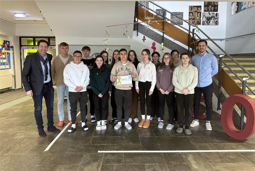 Die Schülerinnen und Schüler der 7B und 7C mit Lehrer Lukas Schattovits und Direktor Markus Neuhold weisen mit der Grünen Schleife auf die Bedeutung seelischer Gesundheit für unser Leben hin.