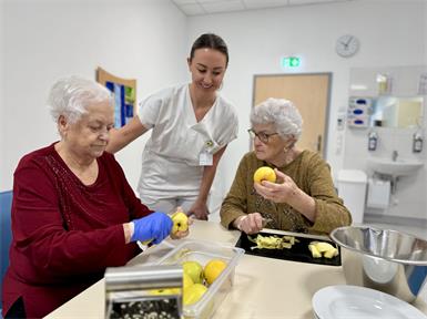 Erika Zapfl und Marica Schaja bereiten gemeinsam mit Diätologin Sandra Maurer Apfelstrudel zu.