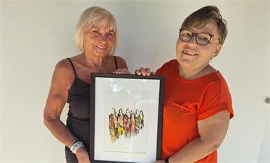 Künstlerin Inge Hauer und die stellvertretende Vorsitzende der Evangelischen Frauenarbeit Agnes Trimmel (r.) zeigen das Titelbild der Einladung zum evangelischen Begegnungstag am 25. September in Eisenstadt.