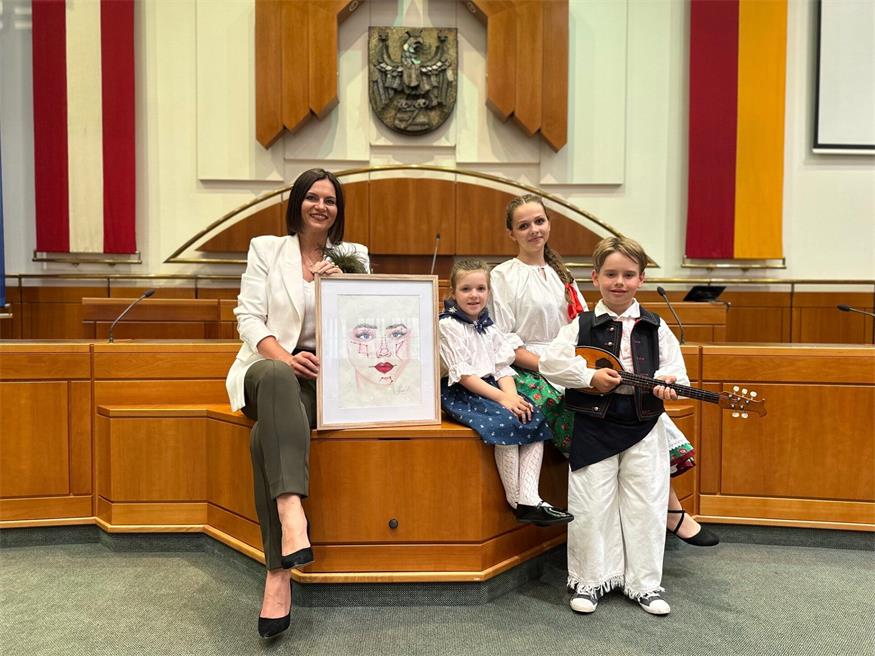 Landtagspräsidentin  Astrid Eisenkopf mit einem Bild der Künstlerin Lisa-Marie Horvath, Hannah von der Kindervolkstanzgruppe Großhöflein, Odette von der ungarischen Tanzgruppe des ZBRG Oberwart und Lovre von der kroatischen Folkloregruppe Poljanci aus Wulkaprodersdorf.