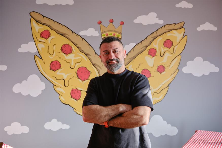 Özkan „Özi“ Kuyumlu in seiner neuen Pizzeria. Das schicke Wandbild ließ er vom Halbturner Betrieb Malerei Zinkl anfertigen.