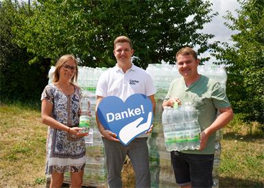 Sabrina Wiedenhofer von Waldquelle, Lukas Szigeti, Bereichsleitung Obdach & Wohnen Caritas Burgenland und Markus Moors von Waldquelle bei der Übergabe von Mineralwasser für die kommende Hitzewelle. 