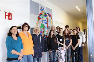 Schülerinnen und Schüler mit Werklehrerin Martina Köppel (l.), Direktorin Carina Werba (r.), den Künstlern Rene Radostics (8.v.r.) und Stefan Blagusz (7.v.r.), Obfrau Eva Messerits (2.v.l.) und Susanne Grössing (3.v.l.) von „Kobersdorf Aktiv“ vor dem fertigen Sportler-Bild. 