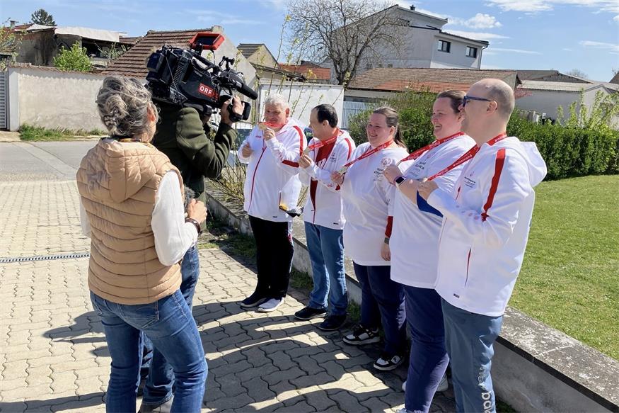 Stolz präsentieren die Klient:innen (v.l.n.r.) Erich Fuhrmann, Samuel Kolar, Andrea Kettner, Beate Kettner und Dominic Bauer ihre Medaillen vor der Kamera des ORF Teams. 